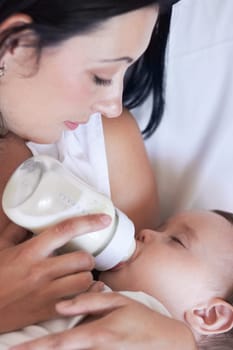 Baby, feeding and mom with child at home with a bottle of milk with parent care with kids. Family, young youth and drink for growth and development with a mother feeling proud from childcare in house.