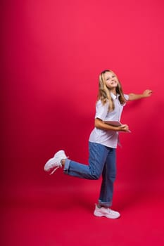 Online school app. Schoolgirl showing tablet computer Empty Screen On red Background. Studio Shot