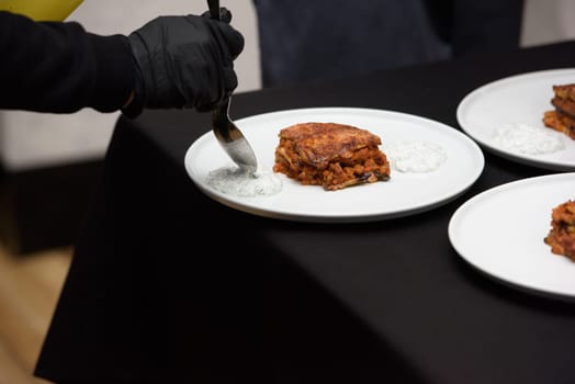 the chef in the restaurant preparing moussaka, baked with beef and cheese