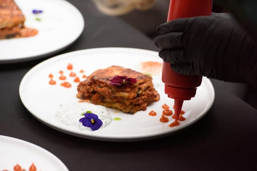 the chef in the restaurant preparing moussaka, baked with beef and cheese