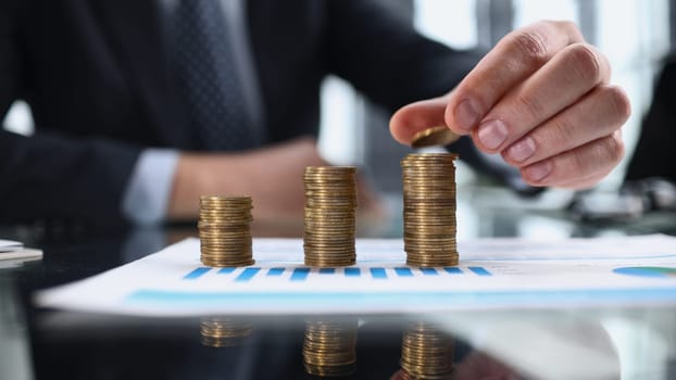 Business, Money, Finance, Secure and Saving Concept. Close up of man hand holding and put a coin to stack of coins table.