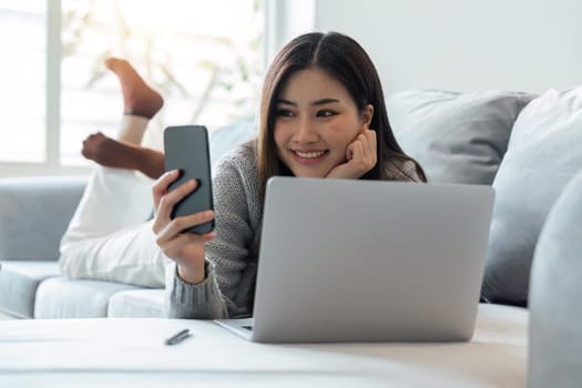 Happy woman enjoy lazy weekend resting on cozy sofa at home using smartphone chatting in social networks, lying on couch in living room.