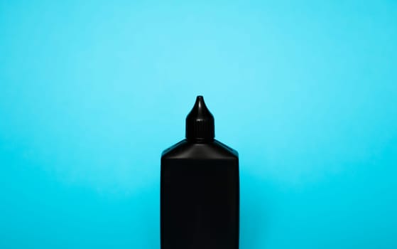 Mock up unbranded black bottle of finish line dry bicycle lubricant with teflon on blue background. Bicycle care, bicycle chain care