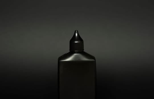 Mock up unbranded black bottle of finish line dry bicycle lubricant with teflon on black background. Bicycle care, bicycle chain care