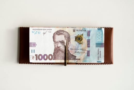 Brown leather money clip, purse with ukrainian hryvnia banknotes. Men's genuine leather wallet. Accessories. Money, financess, economy, saving