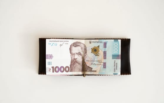 Brown leather money clip, purse with ukrainian hryvnia banknotes. Men's genuine leather wallet. Accessories. Money, financess, economy, saving