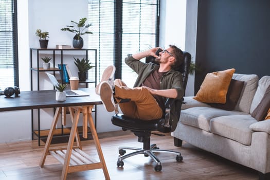 Businessman taking break in office and having conversation on phone while adopting relaxed posture. This image represents the idea of communication and relaxation in a professional setting. High quality photo