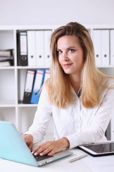 Beautiful businesswoman portrait in office sitting at table smiling and looking at camera teacher expresses success checking control papers