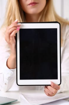 Beautiful businesswoman wearing glasses portrait at the office holding a tablet in hand sitting at the table smiling and looking at the camera teacher expresses success checking the test papers.