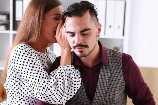 Woman gossip whispers in the ear of news to a man in office