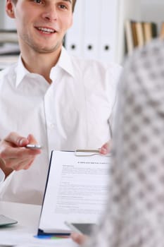 Male arm in white shirt offer contract form on clipboard pad and silver pen to sign closeup. Strike a bargain for profit white collar motivation union decision corporate sale insurance agent concept