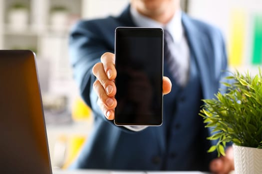 Male arm in suit show in camera phone display screen closeup. Read news mania send sms chat addict use electronic bank modern lifestyle job plan colleague share blog tweet web application search