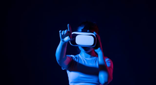 Woman using virtual reality glasses in a studio. Business woman wearing VR goggles and interacts with cyberspace using swipe and stretching gestures
