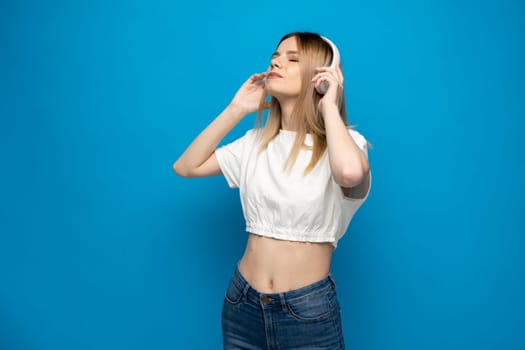 Portraite of lovely cheerful girl listening music isolated over bright blue color background