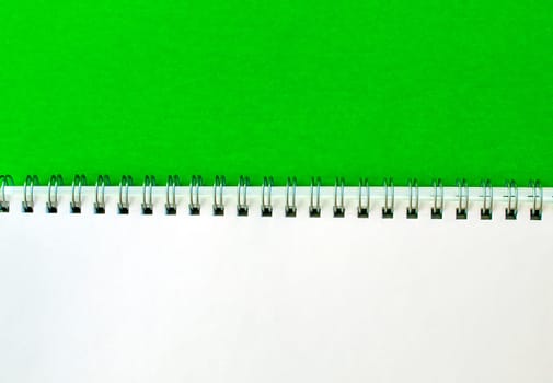 White notepad with a spring on a green background.
School white notebook.