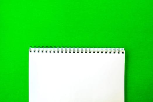 White notepad on a green background. School white notebook with a spring.