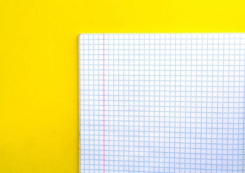 White notebook in a cage on a yellow background. School white notebook in a cage on a yellow background.