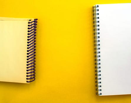 White and beige notepads on a yellow background, empty space in the center. School white and beige notebooks on a yellow background.