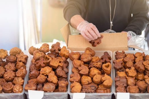 Selection of fresh shaped cookies at the market. A man puts cookies of various shapes on the counter in a pastry shop. Festive baking. High quality photo