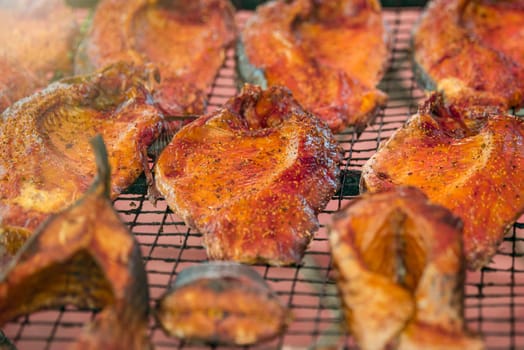 Hot smoked salmon. Large pieces of Atlantic salmon are smoked on a smokehouse grate close-up. Fish smoking plant. High quality photo