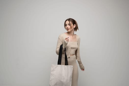 Brunette young girl holding linen shopping bag, mock up. Lady holding flax shopper handbag. Fashion and ecology concept