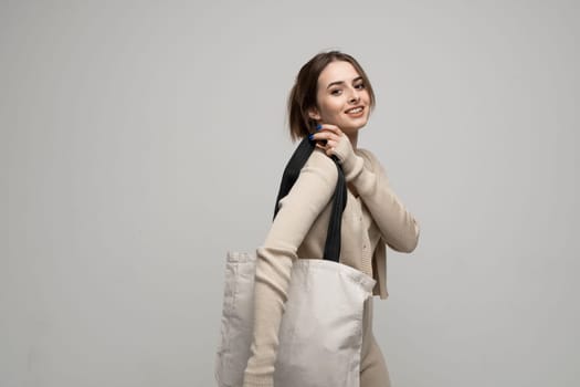 Brunette young girl holding linen shopping bag, mock up. Lady holding flax shopper handbag. Fashion and ecology concept