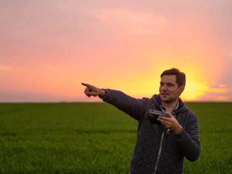 Man portrait operating the drone by remote control at sunset magic golden hour. Filming night landscape