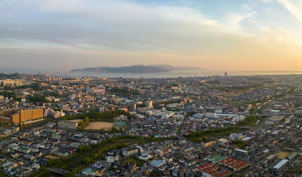 Sprawling coastal city and suspension bridge to offshore island at sunset. High quality photo