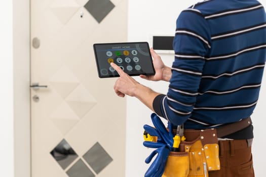 an electrician repairs an intercom with a tablet.