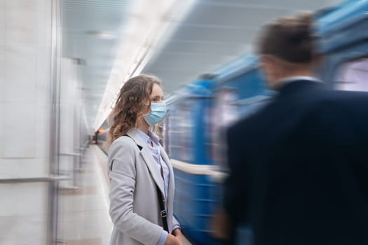 young woman in protective mask standing at subway station. urban lifestyle.