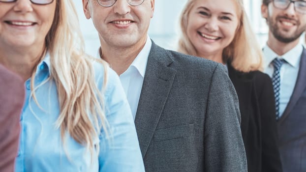 close up. confident young businessman standing in front of his colleagues. business concept