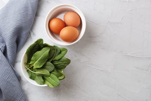 Plate with fresh organic sorrel leaves and eggs on a gray background.First spring greens. Healthy food concept. copy space