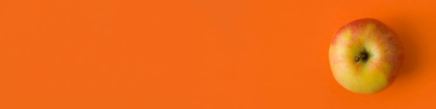 Banner. Apple on an orange background close-up, photo.