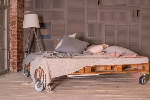 loft apartment interior.Minimalist interior with simple wooden bed, lamp, big window.Stylish bedroom in loft style pastel colors.