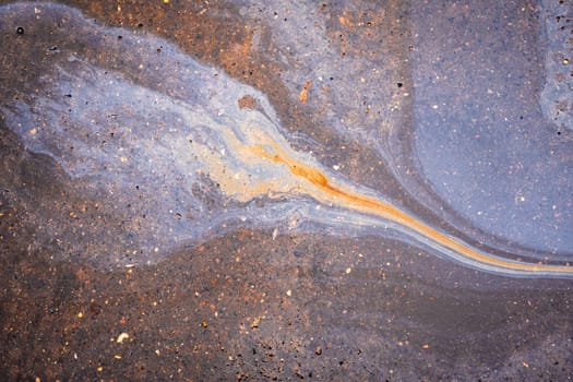 Rainbow gasoline oil spill on the pavement as a texture or background.