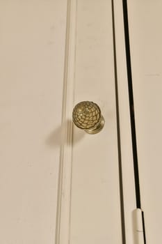 a door handle on the side of a white cabinet with peeling paint and chip marks that have been painted off