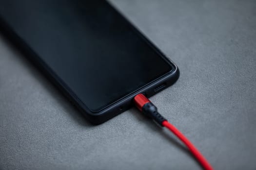 Charging the battery of a cell phone by connecting it with a wire to an electric charger.