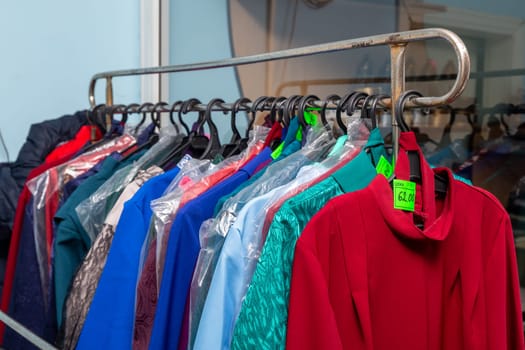 Hangers with men suits and women clothes for the deceased in a funeral goods store. The clothes in which the deceased is escorted to the last journey.