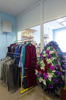 Hangers with men suits and women clothes for the deceased in a funeral goods store. The clothes in which the deceased is escorted to the last journey.