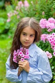 Portrait of a adorable little girl with pink phlox flowers, summer. Close up. Vertical