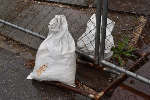 Sandbags Holding A Construction Fence on a Rainy Day. High quality photo