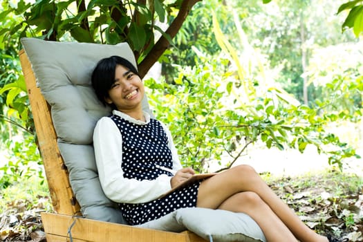 Beautiful young asian woman smiling and happy in garden, attractive female learner studying at garden