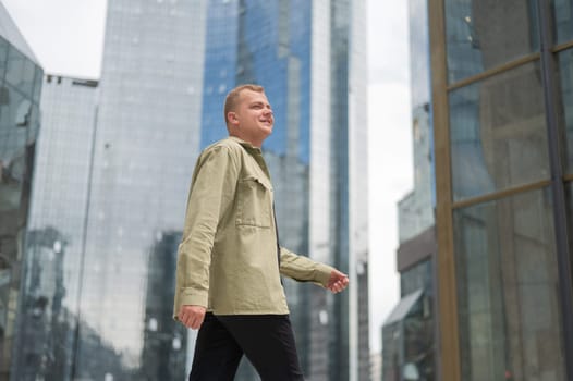 A happy man stands against the backdrop of a skyscraper with his arms spread out to the sides like wings