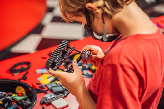 A boy in a medical mask plays with a constructor. child playing and building with colorful plastic bricks table. Early learning and development.