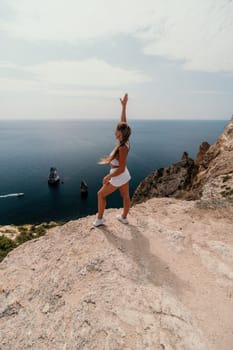 Woman travel sea. Happy tourist in hat enjoy taking picture outdoors for memories. Woman traveler posing on the beach at sea surrounded by volcanic mountains, sharing travel adventure journey