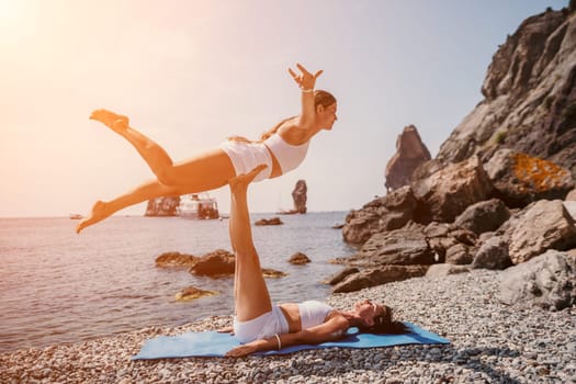 Woman sea yoga. Back view of free calm happy satisfied woman with long hair standing on top rock with yoga position against of sky by the sea. Healthy lifestyle outdoors in nature, fitness concept.