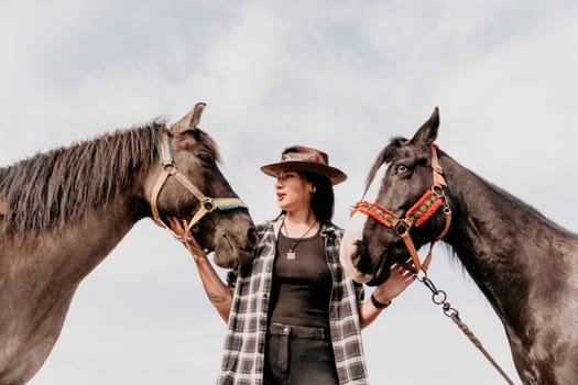 Cute happy young woman with horse. Rider female drives her horse in nature on evening sunset light background. Concept of outdoor riding, sports and recreation.