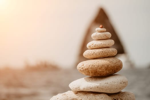 Pyramid stones on the seashore with warm sunset on the sea background. Happy holidays. Pebble beach, calm sea, travel destination. Concept of happy vacation on the sea, meditation, spa, calmness.