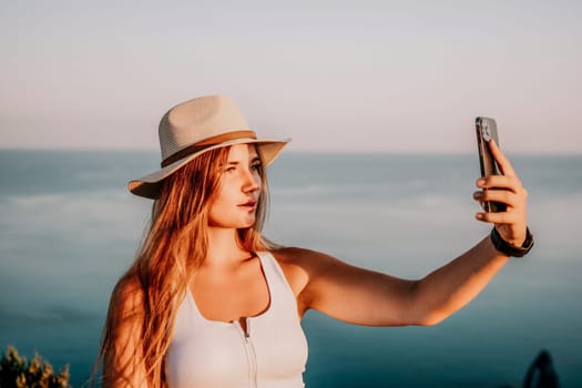 Woman travel sea. Happy tourist in hat enjoy taking picture outdoors for memories. Woman traveler posing on the beach at sea surrounded by volcanic mountains, sharing travel adventure journey