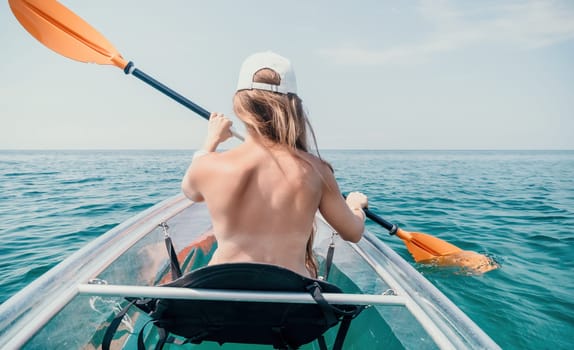 Woman in kayak back view. Happy young woman with long hair floating in transparent kayak on the crystal clear sea. Summer holiday vacation and cheerful female people having fun on the boat.